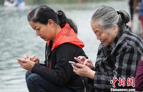 图为中国中老年女性使用智能手机上网。(资料图)<a target=